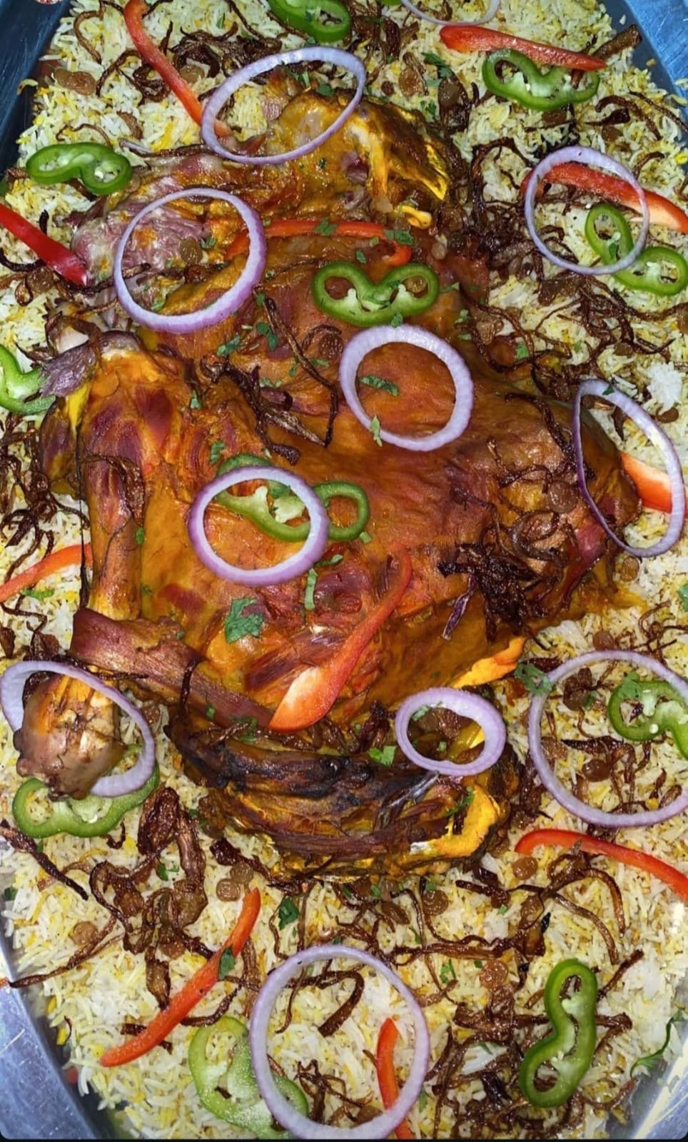 Whole roasted lamb leg over saffron rice with onion and pepper rings