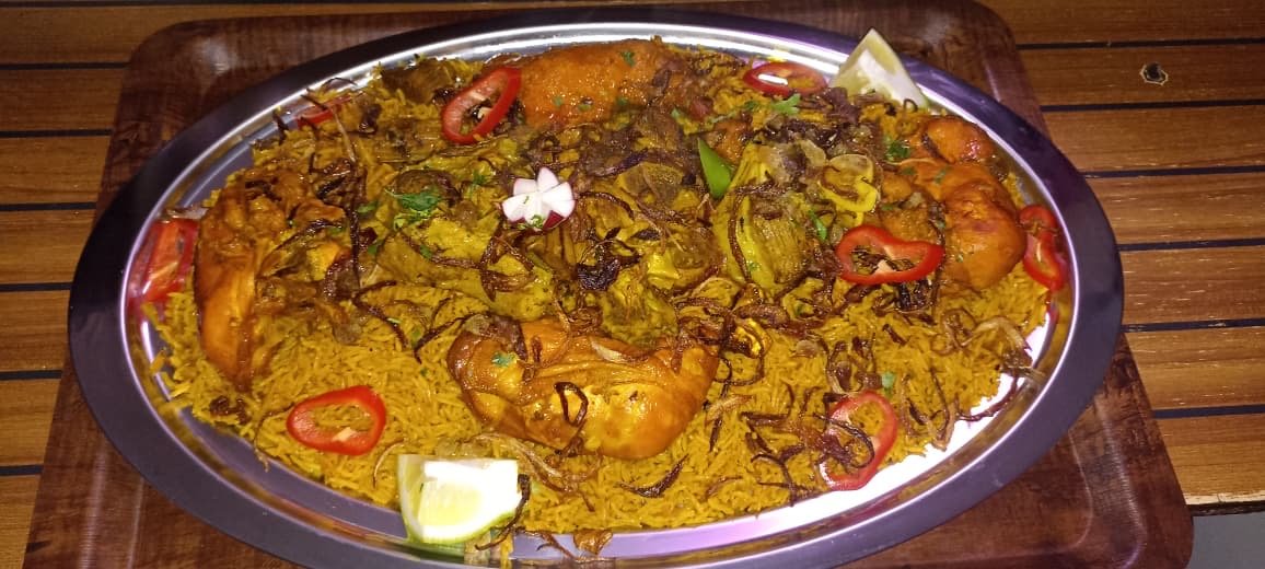 Chicken mandi platter on saffron rice with peppers and lemon