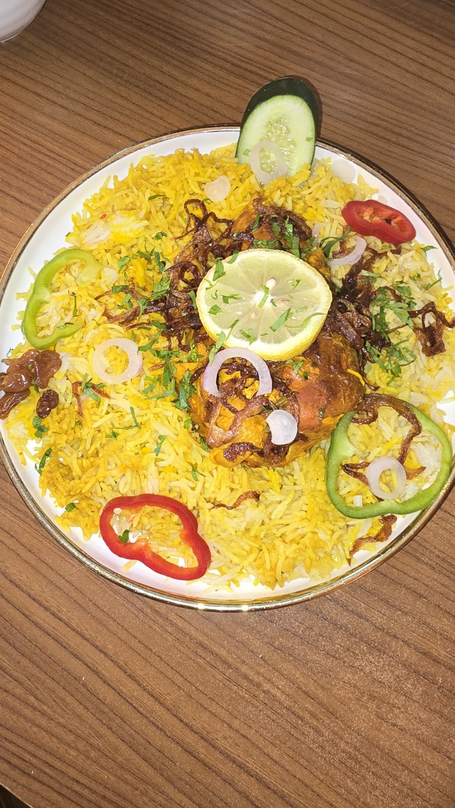 Chicken kabsa with raisins, onion rings and pepper garnish